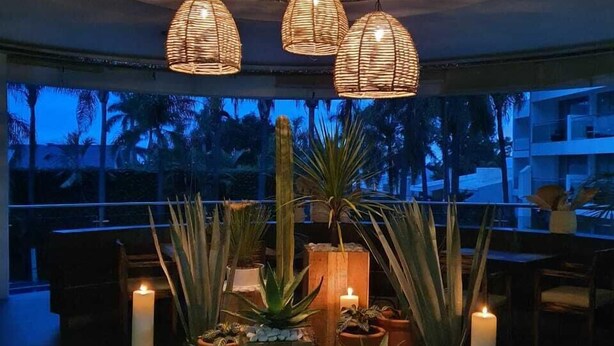 A well-lit indoor space with a circular seating area surrounded by potted plants and candles, featuring a ceiling with a unique textured design. - Hotel Río 1300 (Cuernavaca)