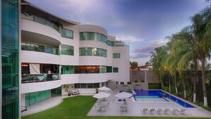 A modern building with a pool, outdoor seating, and a well-maintained lawn. - Hotel Río 1300 (Cuernavaca)