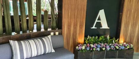 A modern lobby with a grey sofa, a wooden accent wall, and a large 'A' sign.