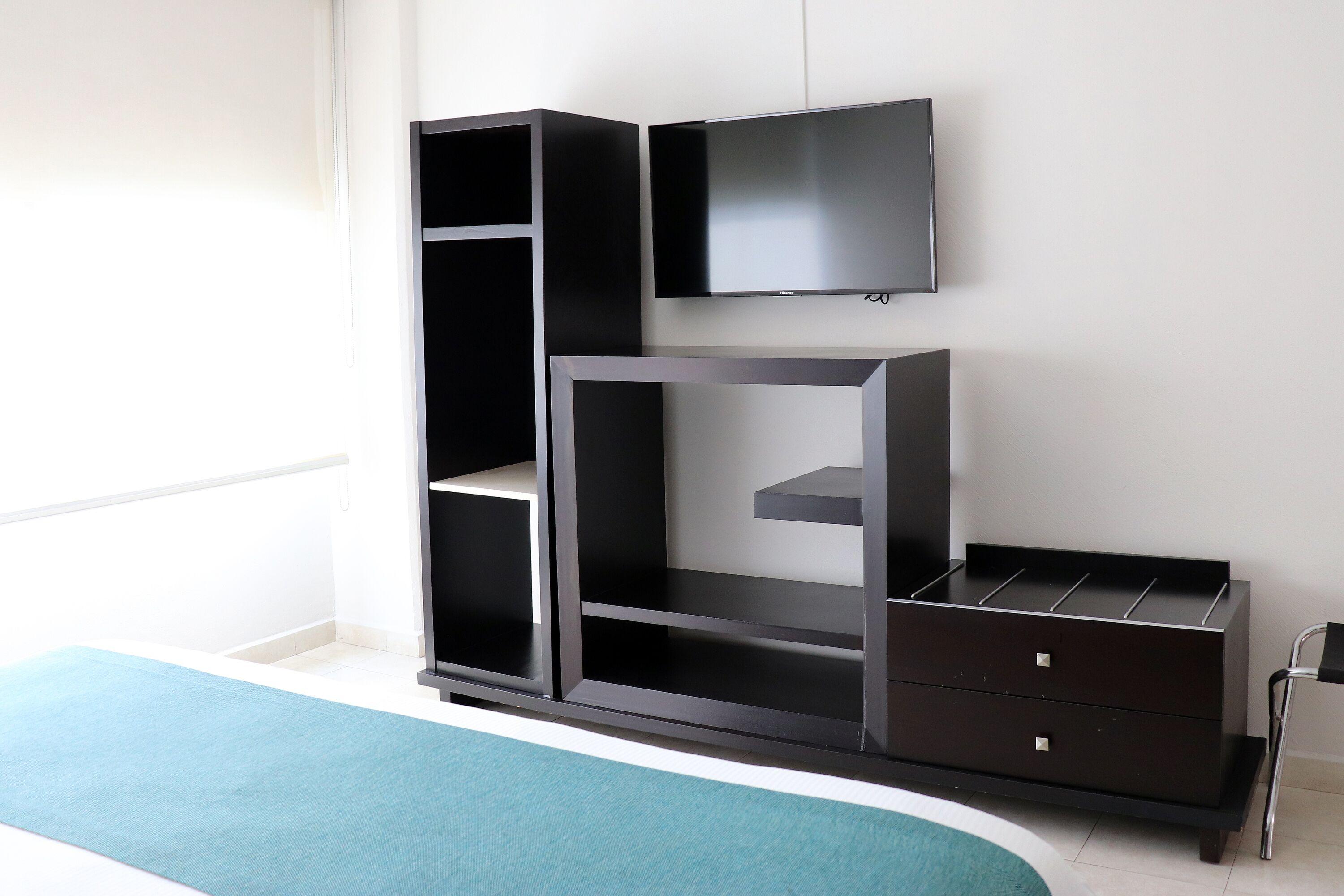 Una habitación moderna con una unidad de entretenimiento negra, un televisor de pantalla plana y una pared de acento color verde azulado.