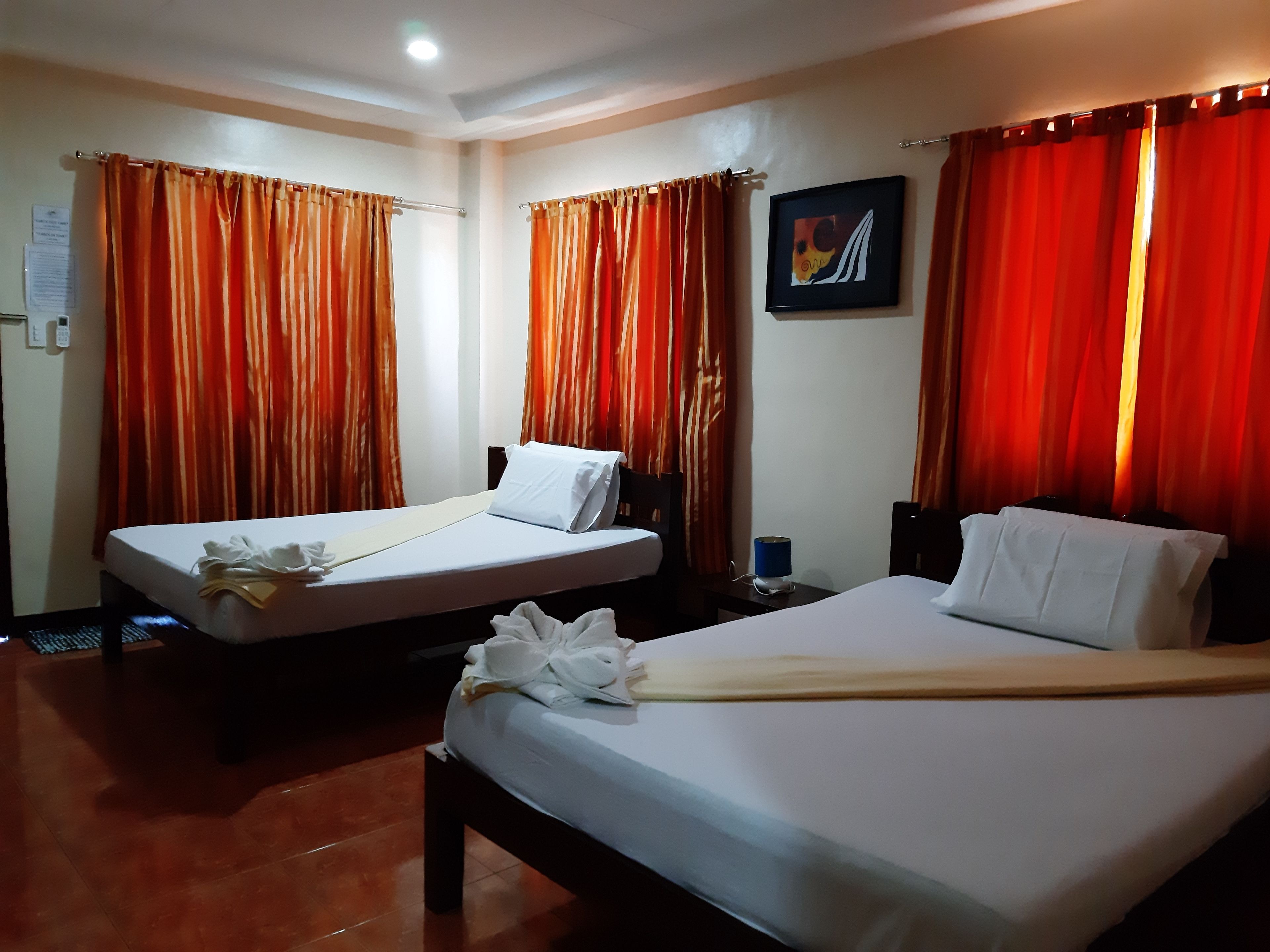 A hotel room with two beds, a desk, a chair, and a painting on the wall.