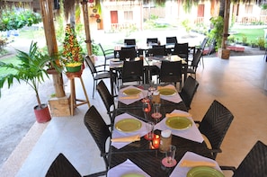 Guests can dine al fresco in this charming outdoor space, surrounded by lush greenery and a Christmas tree.