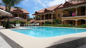Relax by the clear blue pool surrounded by a tiled deck and picturesque buildings with balconies.