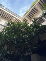 Un edificio de varios pisos con balcones, un patio central y abundante vegetación.