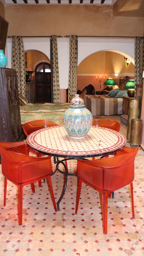 Zona pranzo con un tavolo rotondo, sedie rosse e un vaso decorativo.