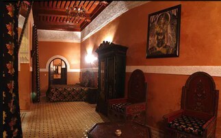 Una habitación con alfombra estampada, un armario de madera, un sofá y un cuadro en la pared.