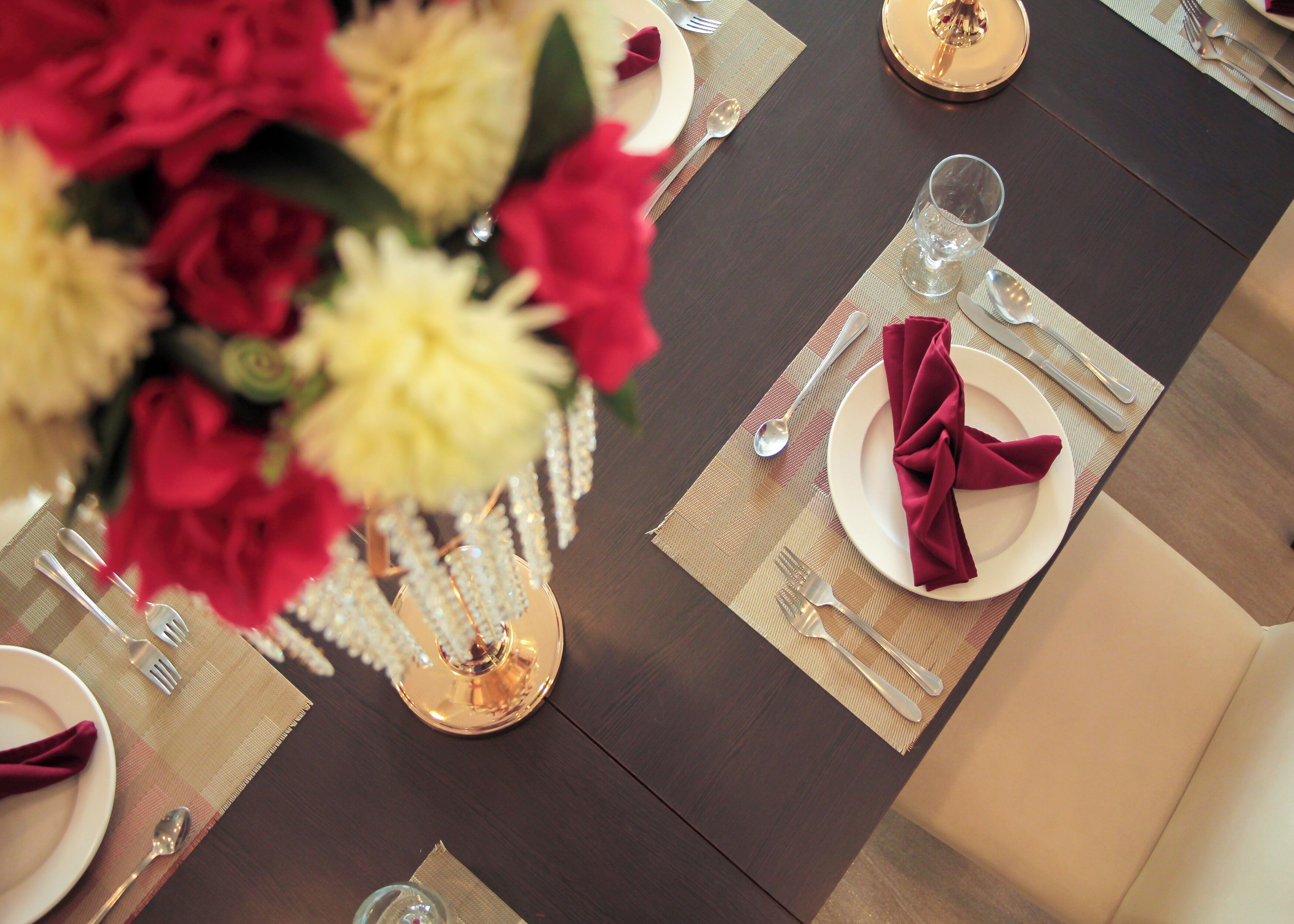 A dining table set with plates, cutlery, and a vase of flowers.