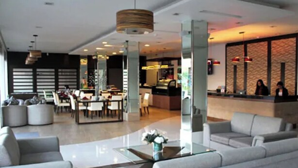 Un moderno vestíbulo de hotel con mostrador de recepción, zona de estar y comedor.