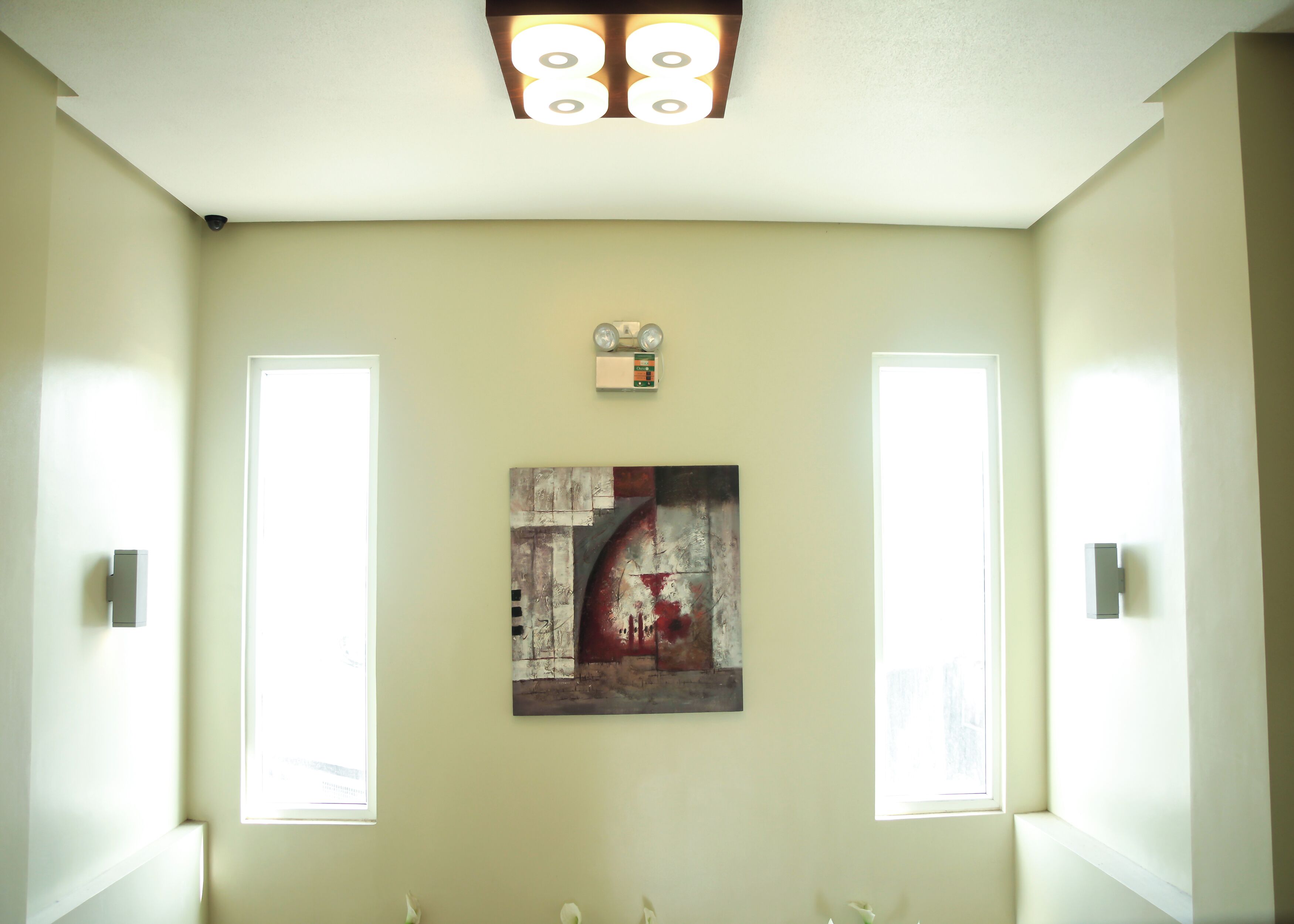 A bathroom with a large mirror, a ceiling light fixture, and a wall-mounted artwork.