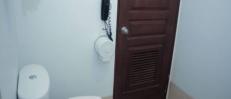 A bathroom with a toilet, a towel rack, a paper towel dispenser, and a door.