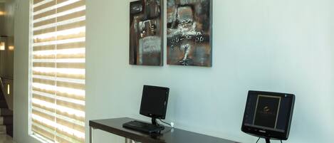 Un espacio de oficina moderno con dos monitores en un escritorio, un teclado y un ratón. Hay obras de arte abstractas de metal en la pared.