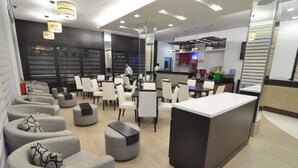 Un moderno vestíbulo de hotel con áreas de descanso, una recepción y un bar.