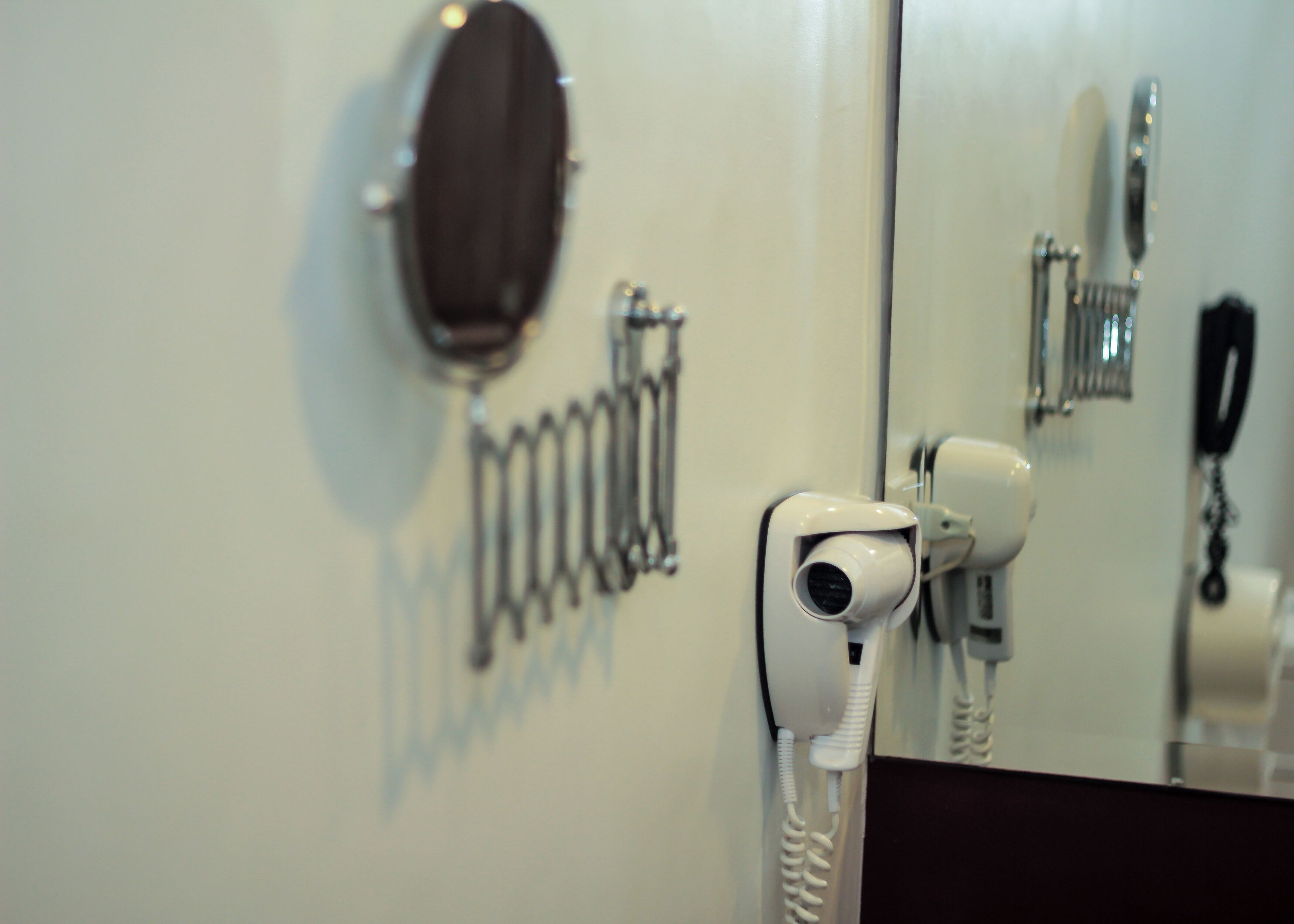 A hairdryer and a telephone mounted on a wall.
