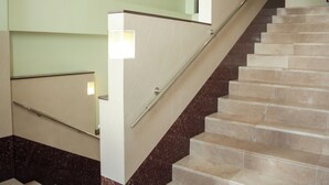 Una escalera con barandilla y una lámpara en la pared.