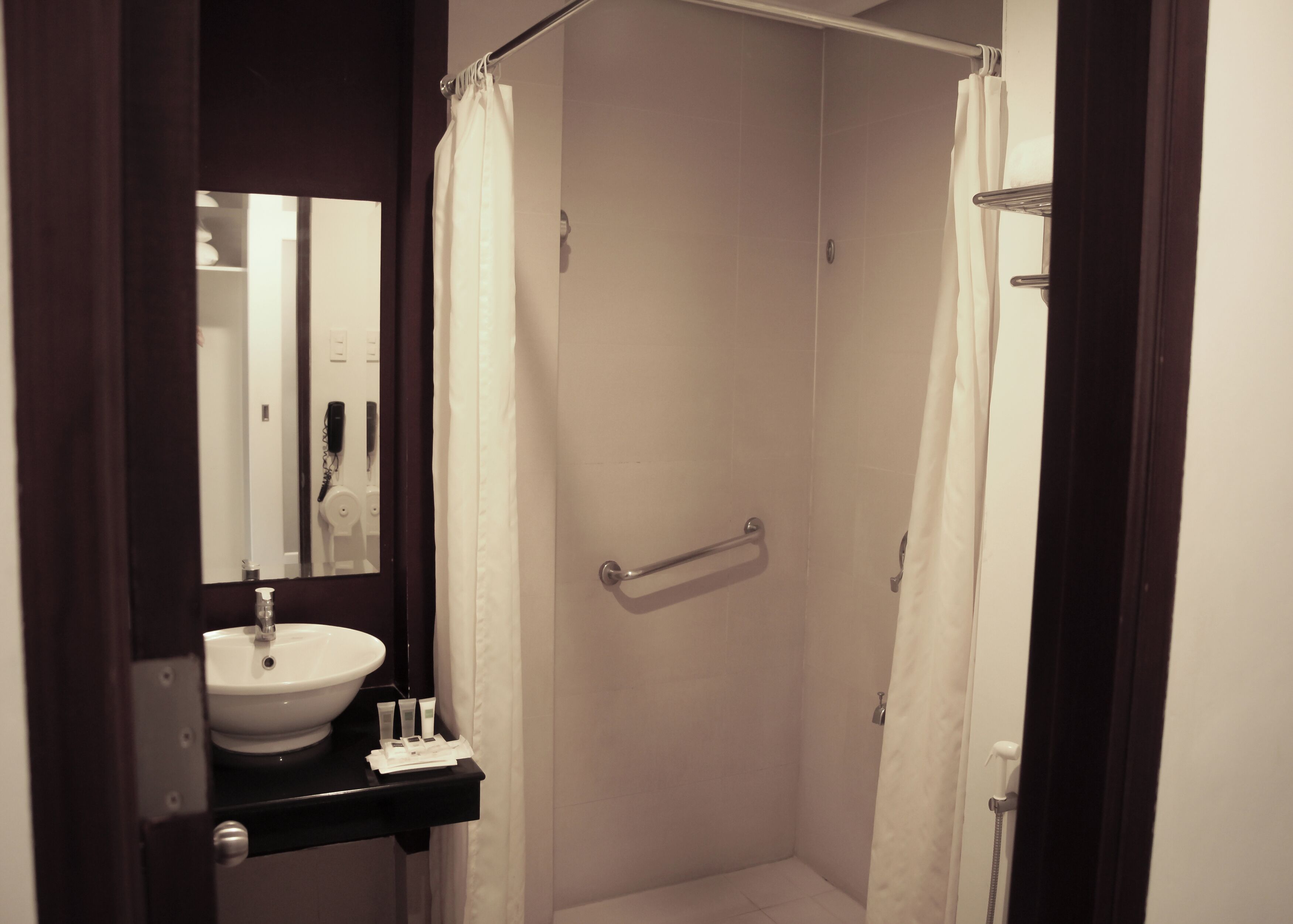 A bathroom with a sink, mirror, and shower.