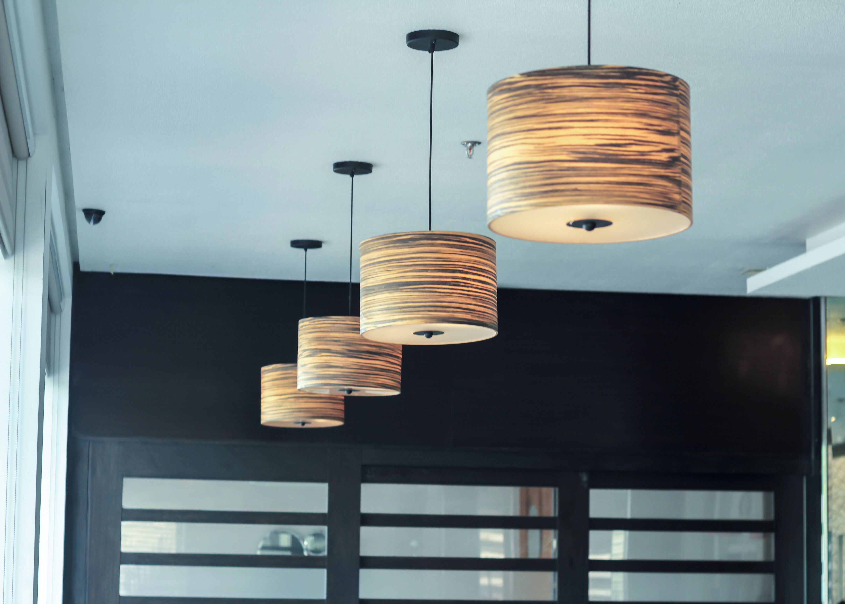 A modern interior with three hanging cylindrical pendant lights with a wood-like texture.