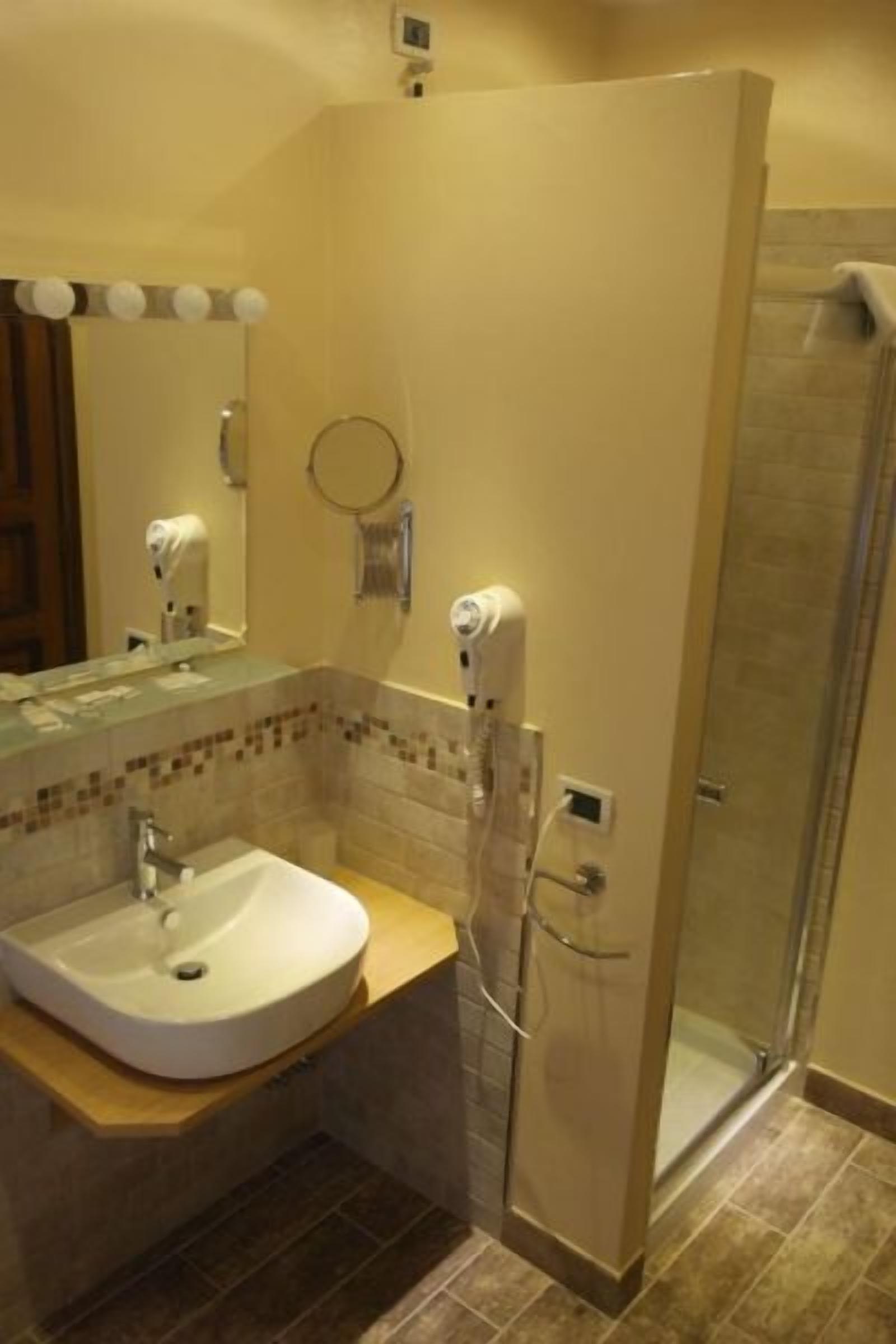 Ein Badezimmer mit Waschbecken, Spiegel, Handtuchhalter und Dusche.