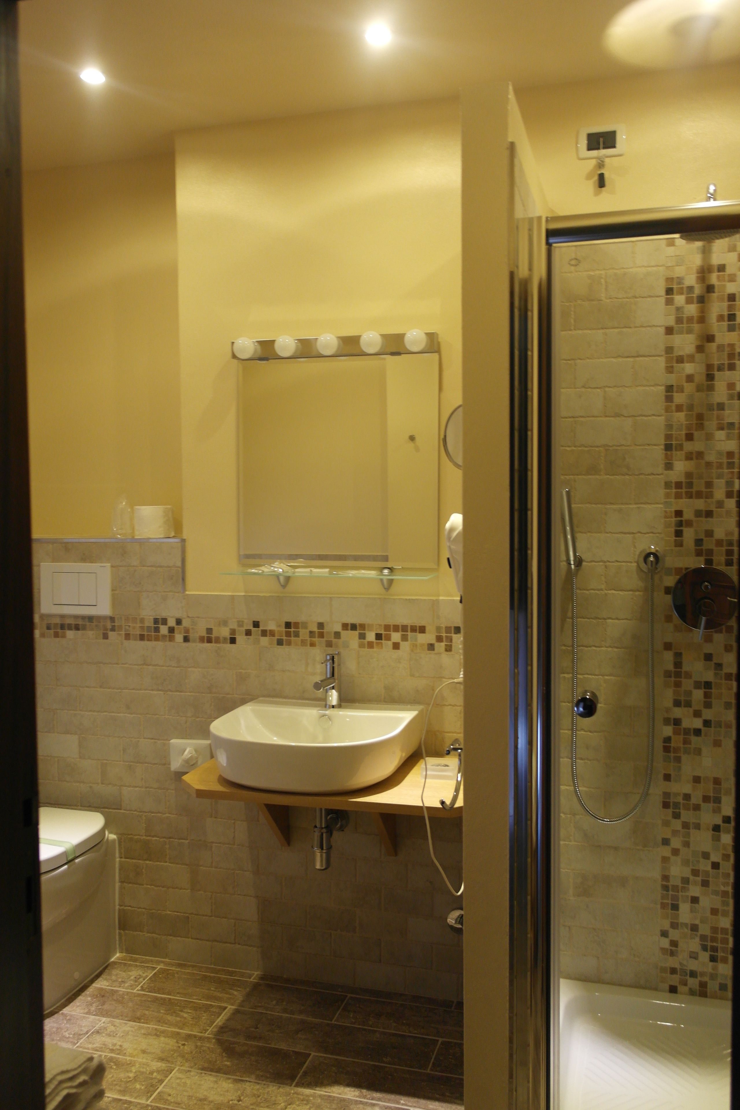 A bathroom with a sink, mirror, and shower.