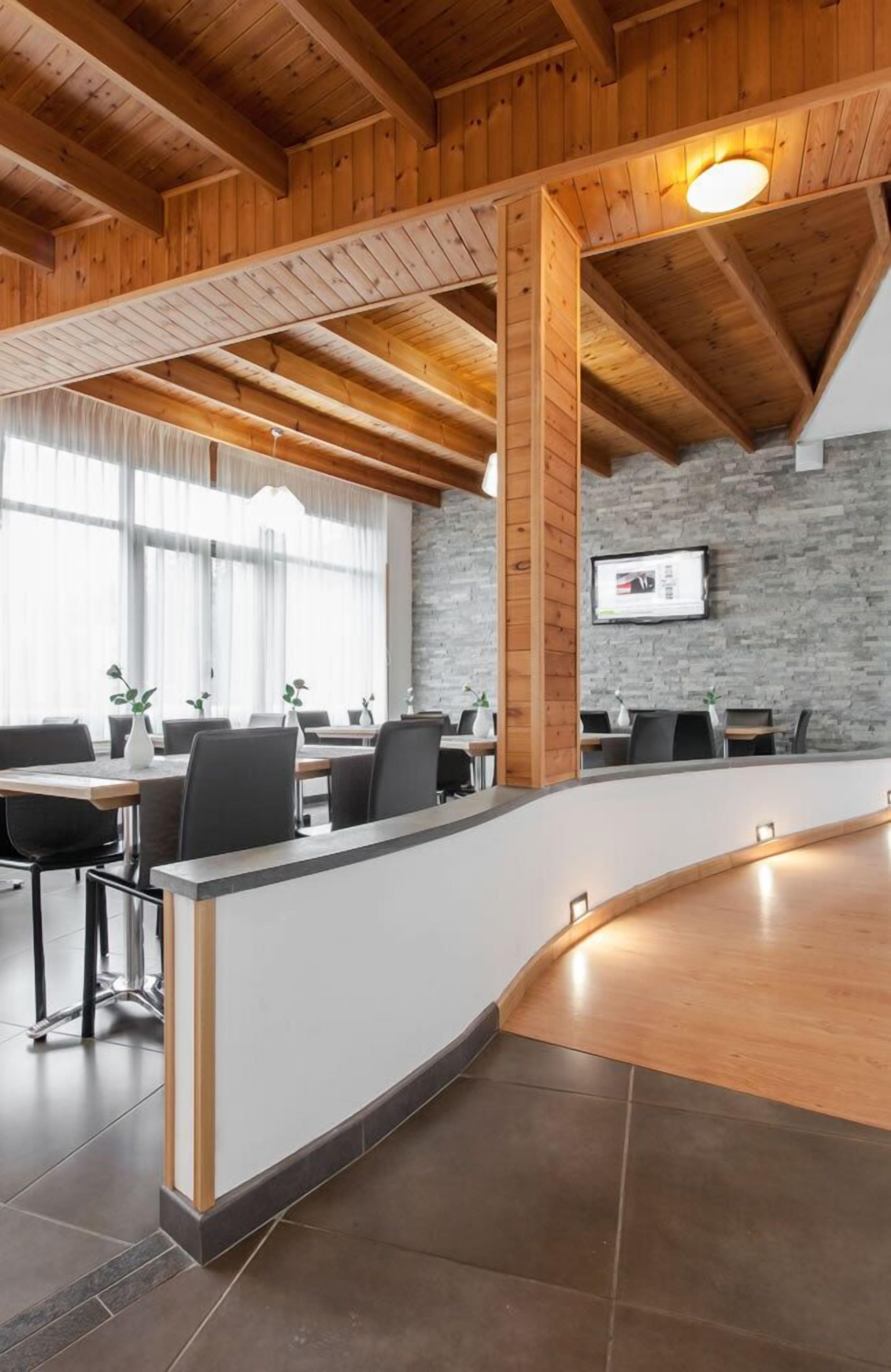 Una sala de conferencias moderna con vigas de madera, un mostrador de recepción curvo y una pared de piedra.