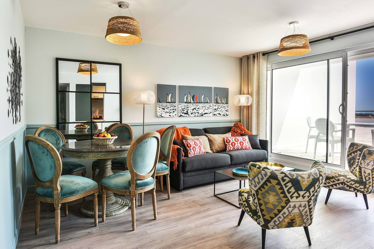 Una sala de estar moderna con comedor, que incluye un sofá, sillas, una mesa de centro y una obra de arte en la pared.