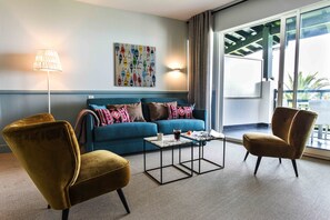 A modern living room with a blue sofa, two armchairs, a coffee table, and a lamp. - Hôtel et Résidence La Réserve (Saint-Jean-de-Luz)