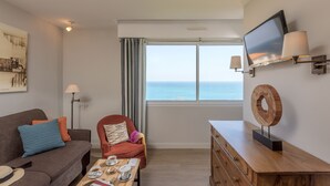 Una sala de estar moderna con un sofá, un sillón, una mesa de centro y un televisor sobre un mueble.