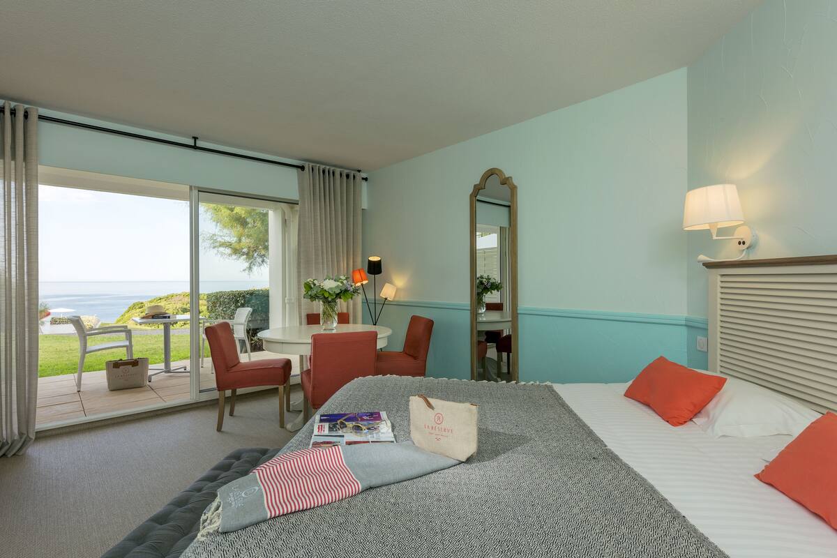 Habitación de hotel con cama, una silla, una mesa y vista al mar.