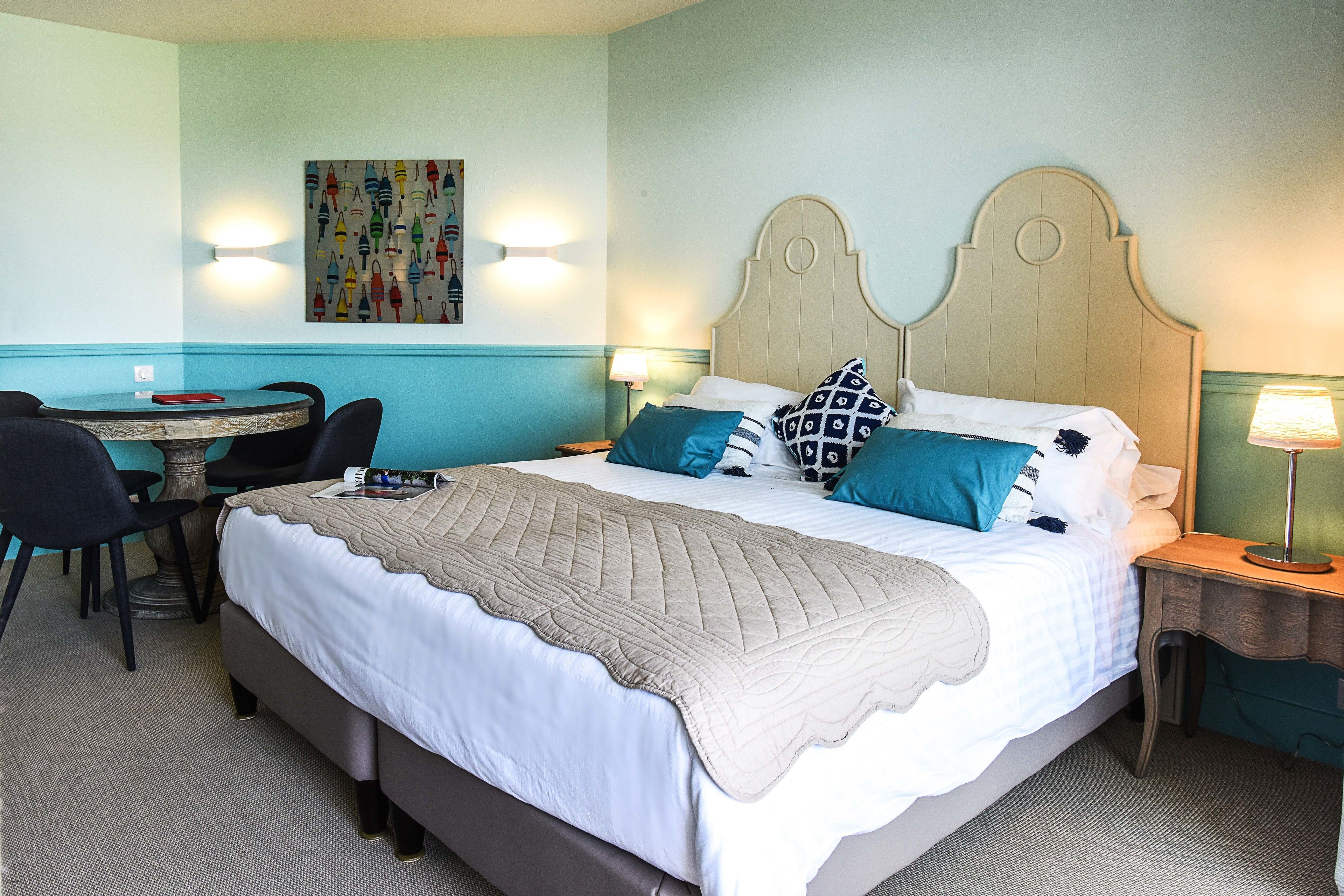 Une chambre d’hôtel bien rangée, avec un lit, des tables de chevet, une chaise et une petite table.