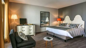 Een moderne slaapkamer met een bed, nachtkastje, lamp, televisie en een bank.