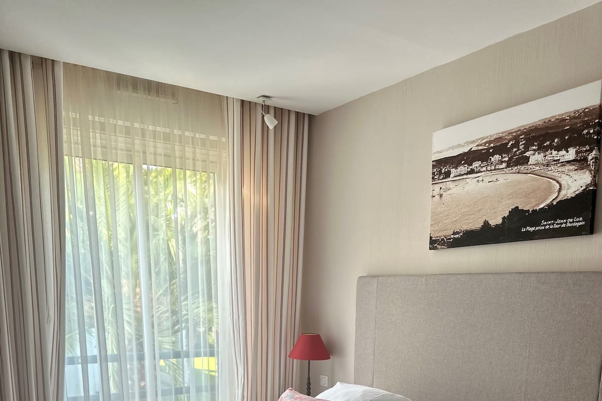 Habitación de hotel con una cama grande, vista a la playa y un cuadro en la pared.