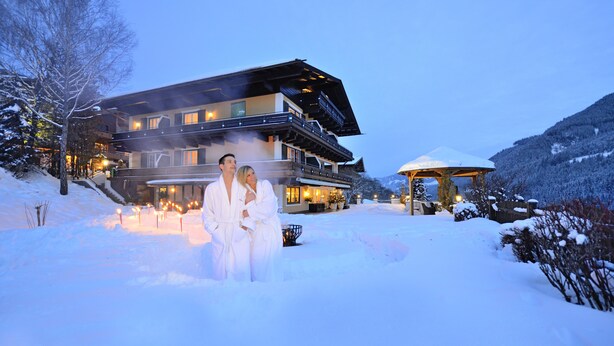 Un hotel moderno con un telesilla, paisajes nevados y una entrada bien iluminada.