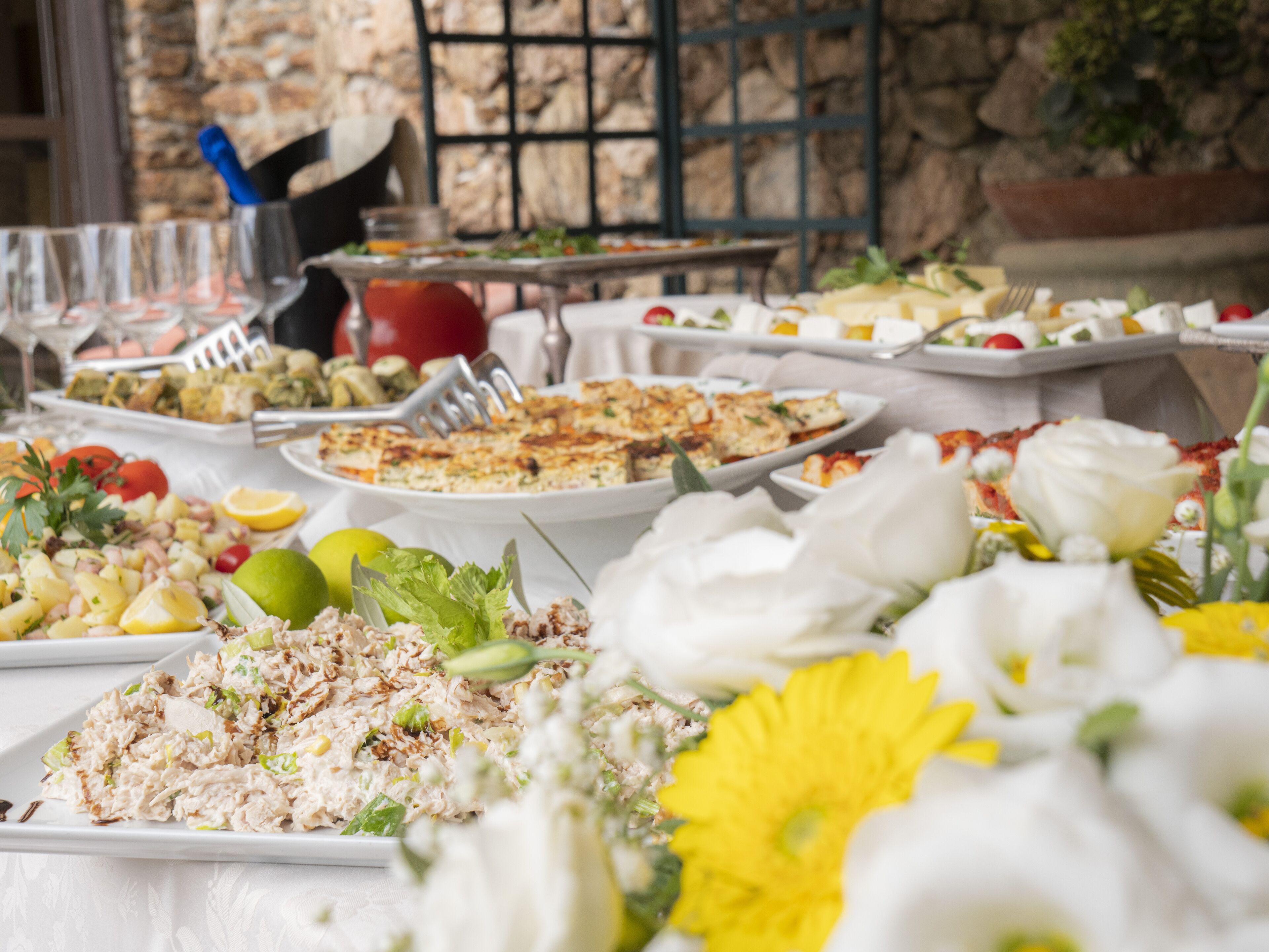 A buffet table with various dishes and a flower arrangement.