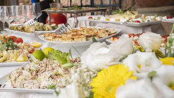 A buffet table with various dishes and a flower arrangement.