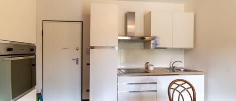 A compact kitchen with white cabinets, a stainless steel sink, and a built-in oven.
