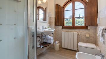 Un bagno moderno con un'ampia finestra, un lavabo, un water e uno spazio doccia.