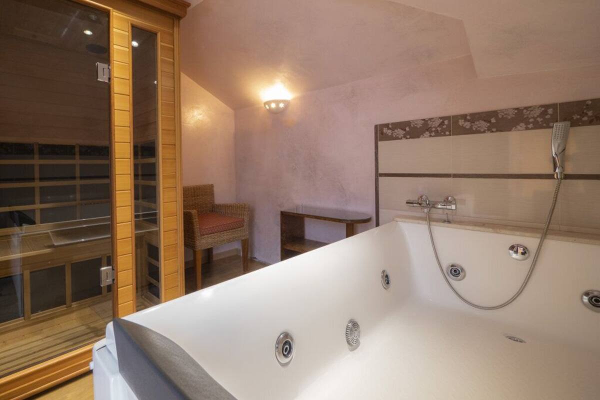 A modern bathroom with a large bathtub, a wooden-framed glass door, and a wall-mounted shower.