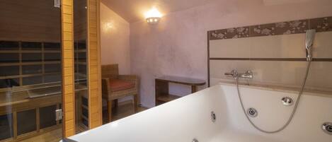 A modern bathroom with a large bathtub, a wooden-framed glass door, and a wall-mounted shower.