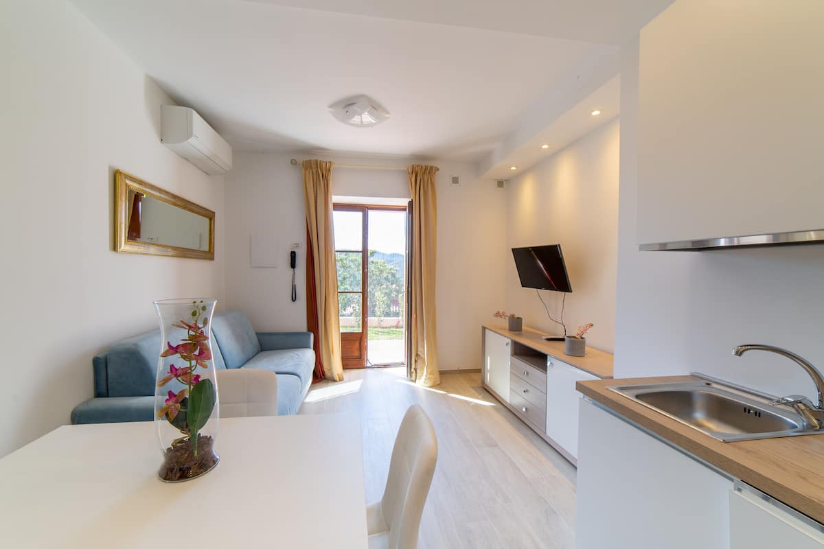 A modern kitchen with a built-in sink, a dining table, and a blue sofa.