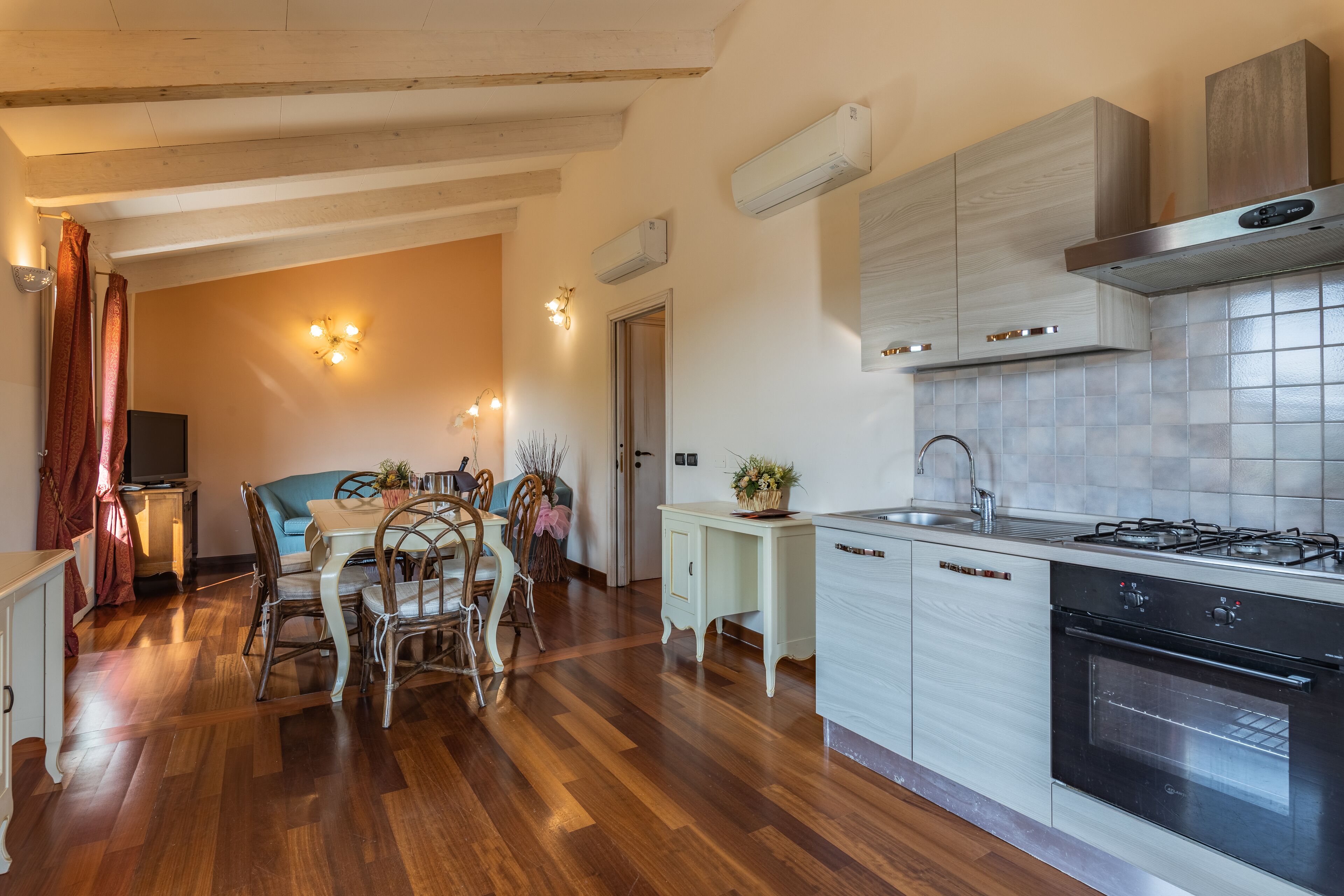 A modern kitchen with wooden flooring, a dining area with a table and chairs, and built-in cabinetry.