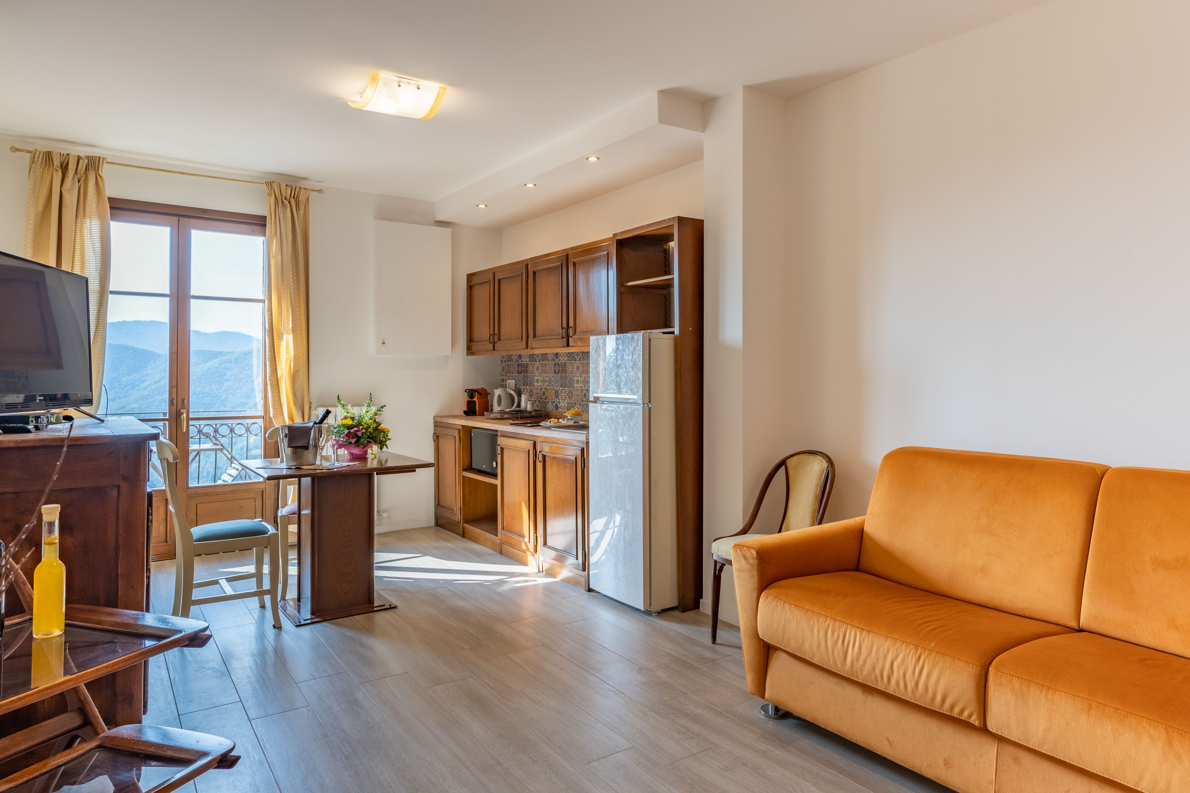 A modern living room with a sofa, a television, and a dining area with a table and chairs.