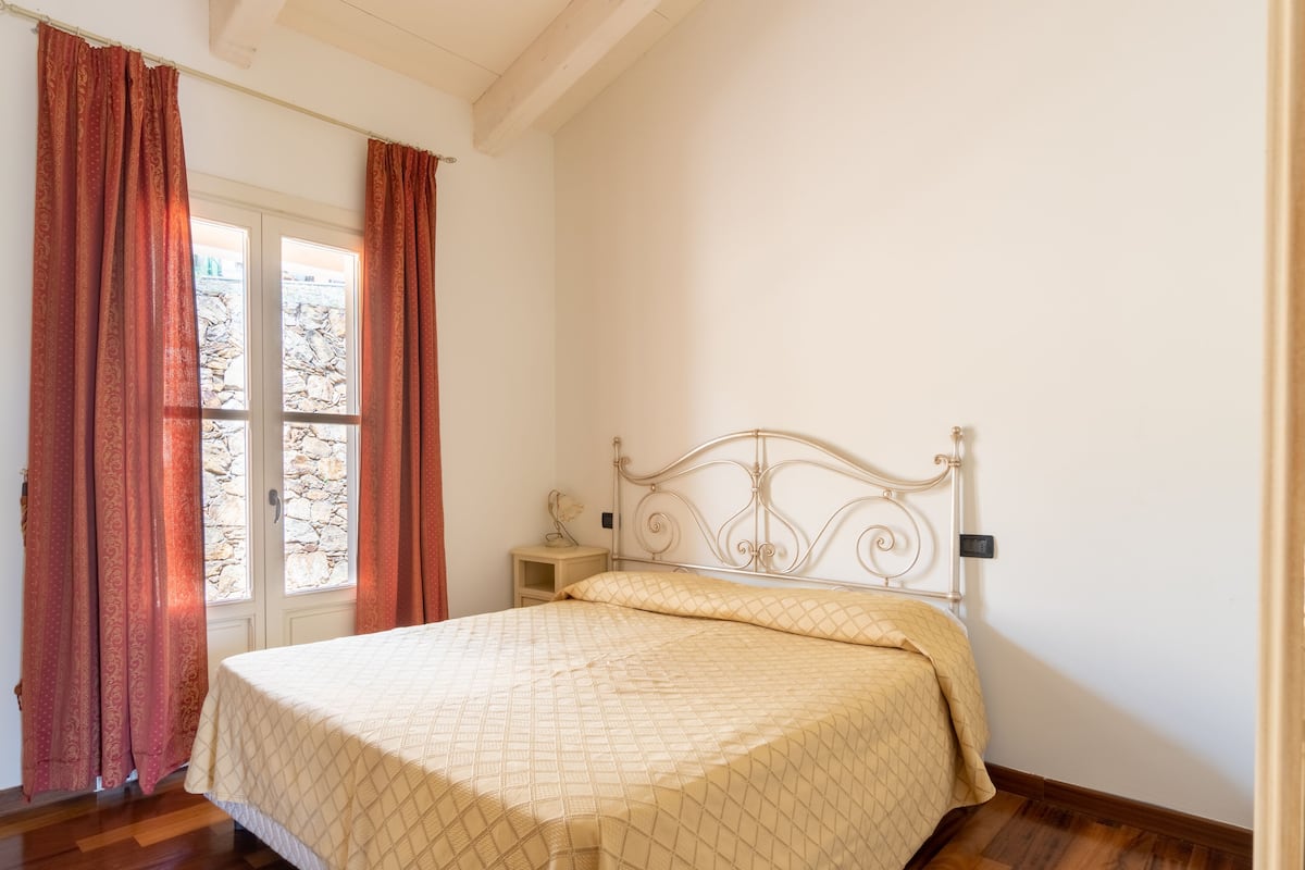 A bedroom with a bed, a nightstand, and a window with curtains.