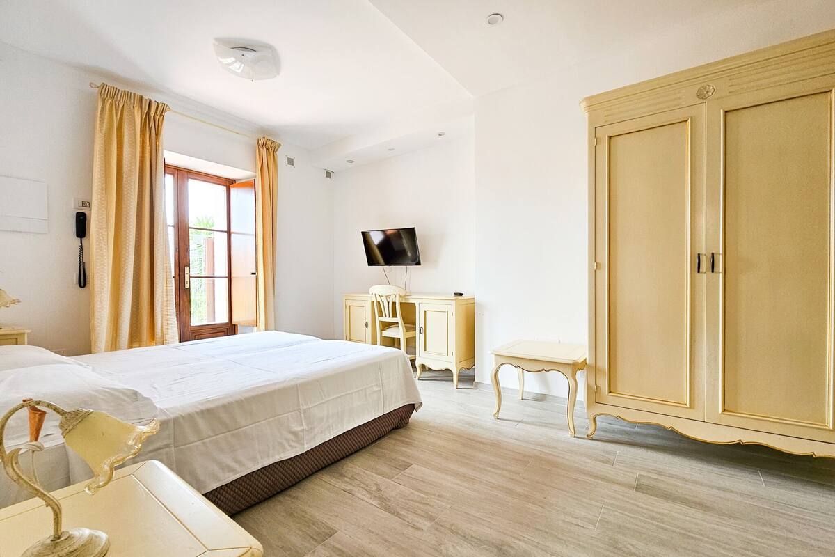 A bedroom with a bed, a desk, a chair, a wardrobe, and a television.