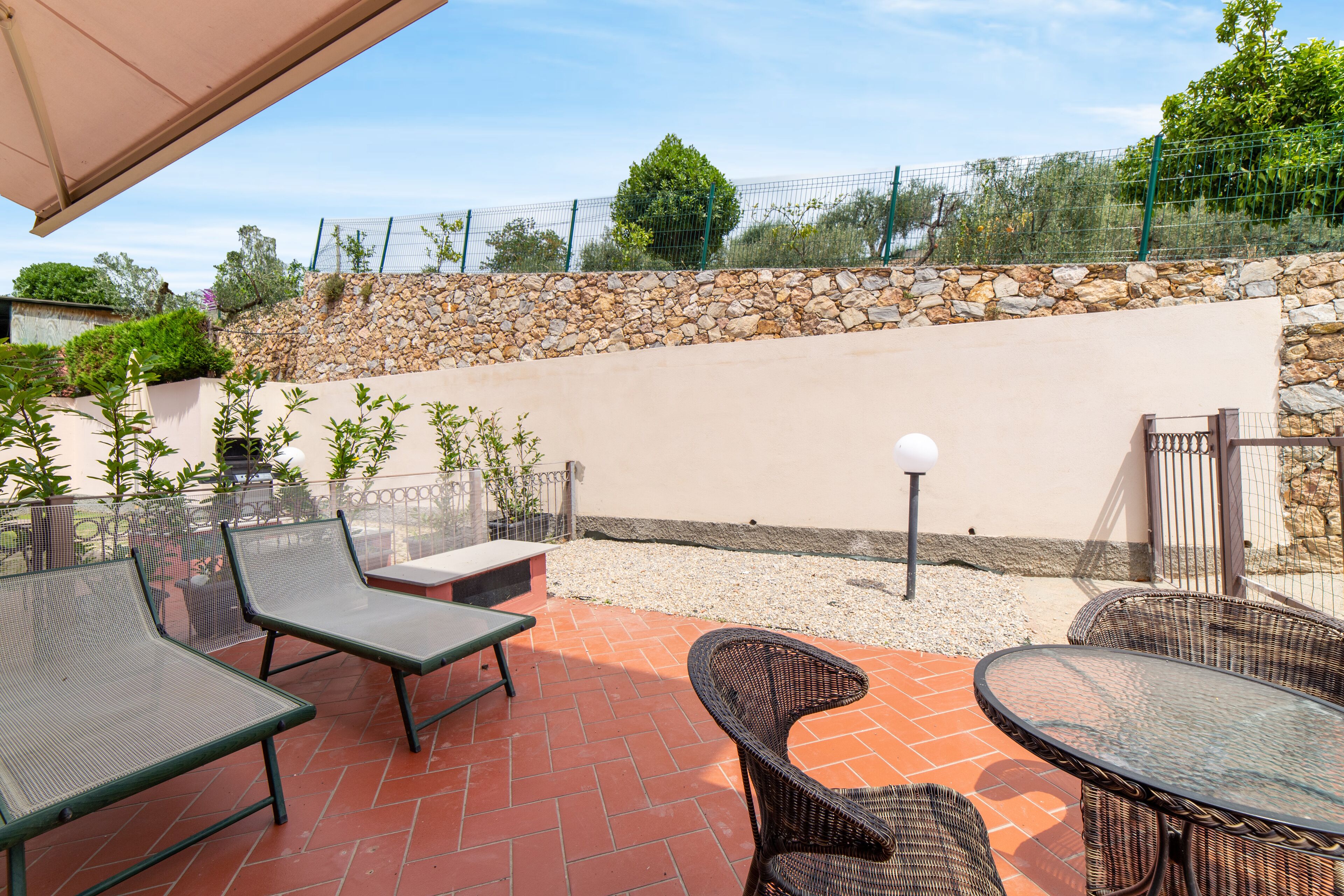 Ein Außenbereich mit Patio, Korbmöbeln, einer Steinmauer und Blick auf die umliegende Landschaft.