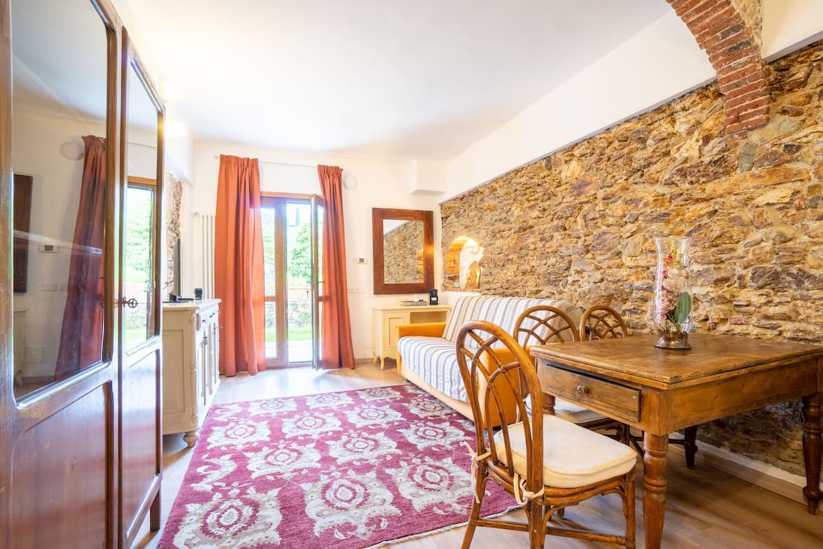 A cozy room with a stone wall, a wooden dining table, and a patterned rug.