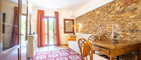 A cozy room with a stone wall, a wooden dining table, and a patterned rug.
