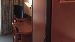 A hotel room with a wooden desk, a television, a lamp, and a wardrobe. - Hotel Brößler (Stockstadt am Main)