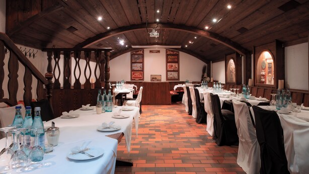 A banquet hall with long tables set for dining, wooden ceiling beams, and framed artwork on the walls. - Hotel Brößler (Stockstadt am Main)