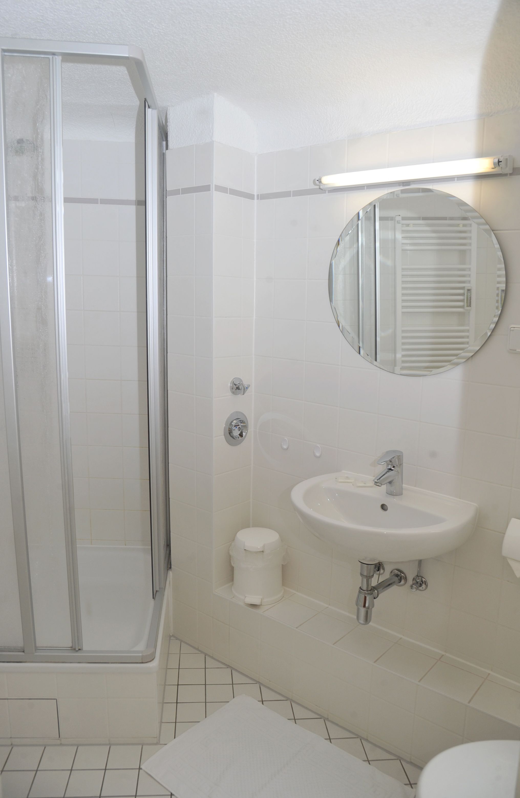 A bathroom with a glass-enclosed shower, a sink with a mirror above it, and a toilet.
