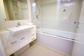 Un baño moderno con ducha de vidrio, lavabo blanco y espejo.