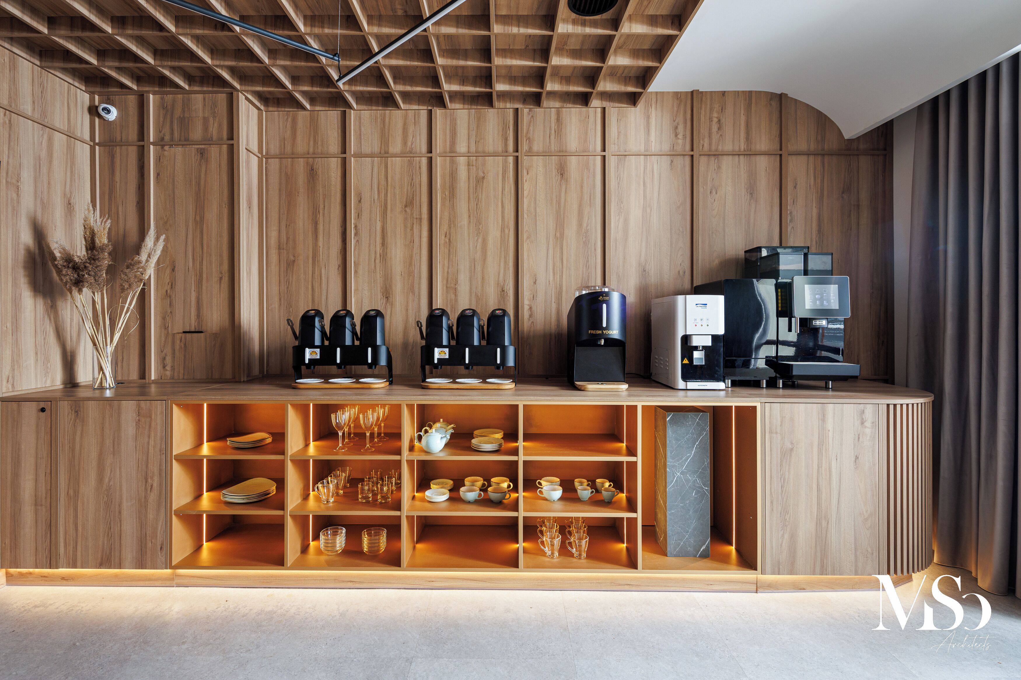 A wooden counter with coffee machines and a variety of glassware and dishes.